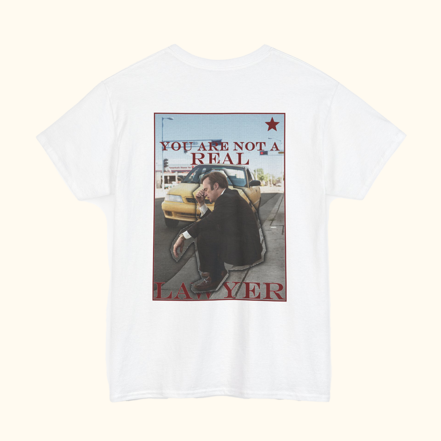 White t-shirt with graphic design of a man sitting on a street and text 'YOU ARE NOT A REAL LAWYER' on a white background.